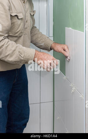 Tiler renovating old bathroom with new ceramic tiles Stock Photo