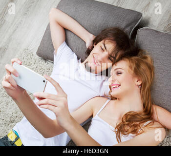 happy young couple relaxing at home and taking a selfie