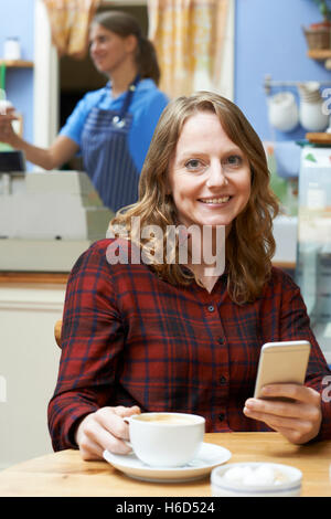 Woman In Coffee Shop Using Mobile Phone Stock Photo