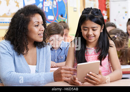Teacher Helping Group Of Elementary School Children In Computer Class Stock Photo