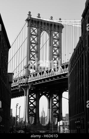 The west pylon of the Manhattan Bridge viewed from Dumbo, Brooklyn, New York.  Empire State Building visible (in B&W). Stock Photo