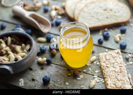 Honey in small glass jar on natural wooden table. Stock Photo