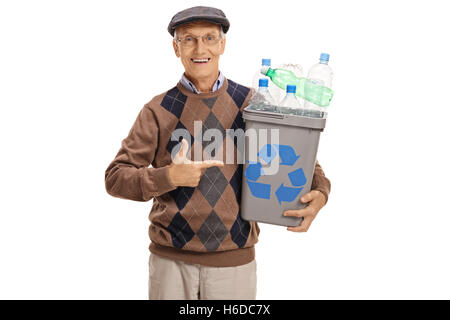 Cheerful elderly man holding a recycling bin full of plastic bottles and pointing isolated on white background Stock Photo