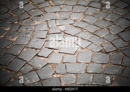 Dark gray cobble road, stone street pavement, background photo with selective focus and vignette effect Stock Photo