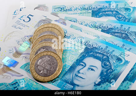 Close up of Queen Elizabeth English money £5 new polymer five pounds bank notes note and two pound coins cash finance concept England UK Great Britain Stock Photo