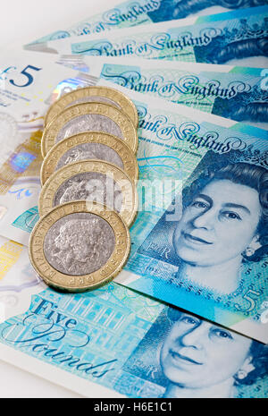 Close up of English money cash new polymer five pound notes and two pounds coins finance concept England UK United Kingdom GB Great Britain Stock Photo