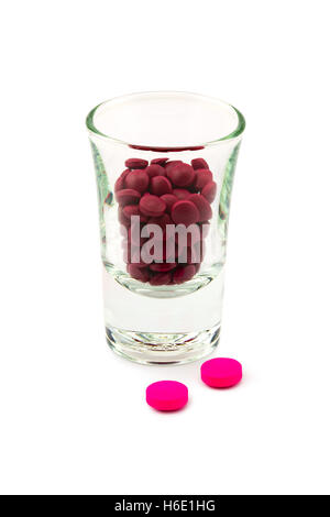 Pills of two kinds of medicine and small glass on white background Stock Photo