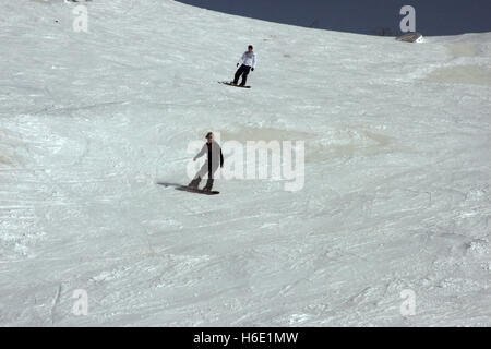 Young snowboarder sliding down snowy slope on mountain at winter