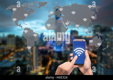 Hand holding mobile phone with wifi icon on world map and city and network connection concept Stock Photo