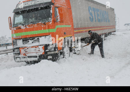 Highway A2, Romania, 17 January 2016: A truck driver shovels snow to free his truck on the closed highway A2, the main commercia Stock Photo