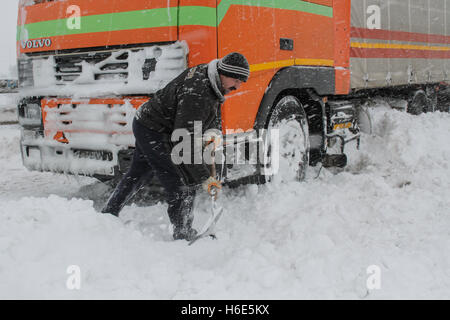 Highway A2, Romania, 17 January 2016: A truck driver shovels snow to free his truck on the closed highway A2, the main commercia Stock Photo