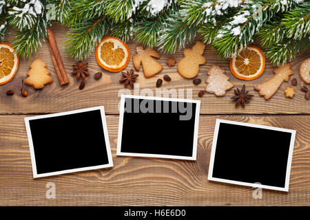 Christmas wooden background with photo frames, snow fir tree, spices and gingerbread cookies Stock Photo