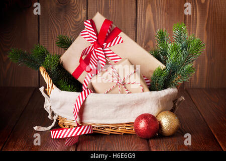 Christmas gift boxes and fir tree branch in basket on wooden table Stock Photo