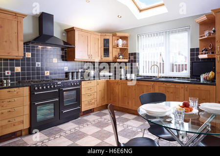 A contemporary, fresh open plan kitchen incorporating a range cooker, hood & wood work surfaces. Glocestershire, UK Stock Photo