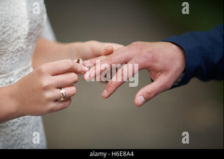bride wears a wedding ring on the finger of groom Stock Photo