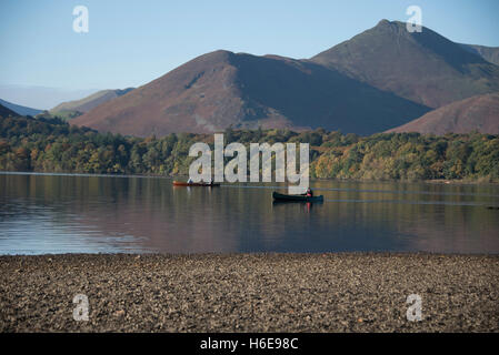 Tranquil autumnal scene at  Keswick, Derwentwater, Cumbria, UK. A canoeist gently paddles across the lake towards the shore. Stock Photo