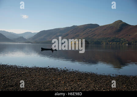 Tranquil autumnal scene at  Keswick, Derwentwater, Cumbria, UK. A lone canoeist gently paddles across the lake. Stock Photo