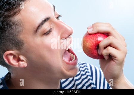 Extreme close up of male teenager about to bite a red apple. Stock Photo