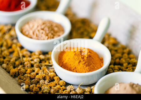 Macro close up of ceramic bowls with dried indian spices.Dried Chamomile flowers on sides. Stock Photo