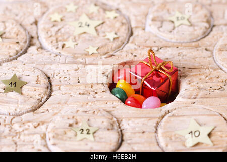 Advent calendar handmade from old timber with open window. Circular space filled with small gift and jelly beans. Stock Photo
