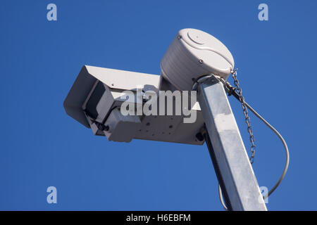 A closed circuit television camera cctv against a clear blue sky Stock Photo