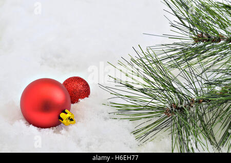 two red Christmas tree balls with fir sprigs on snow background, macro, close up, space for text, horizontal, full frame Stock Photo