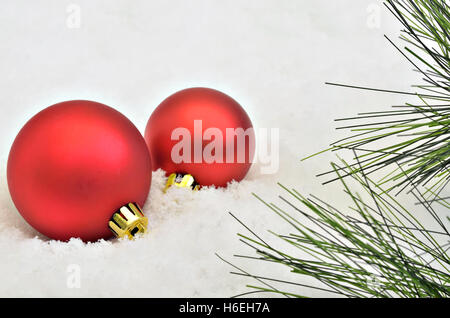 two red Christmas tree balls with fir sprigs on snow background, macro, close up, space for text, horizontal, full frame Stock Photo