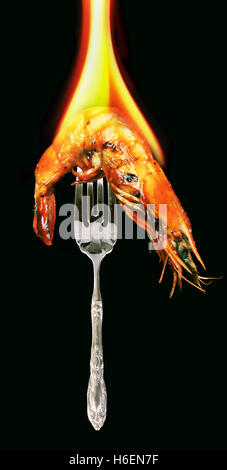 Shrimp on a silver fork with hot fire burning. Stock Photo