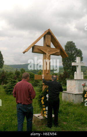 Men praying at wooden crucifix raised in memory of victims of communism in Sighet, Romania Stock Photo