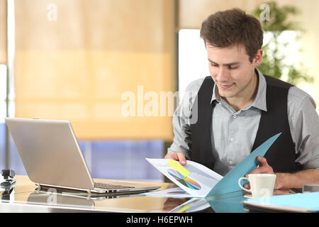 Businessman working watching statistics in a paper document sitting in a desk at office Stock Photo
