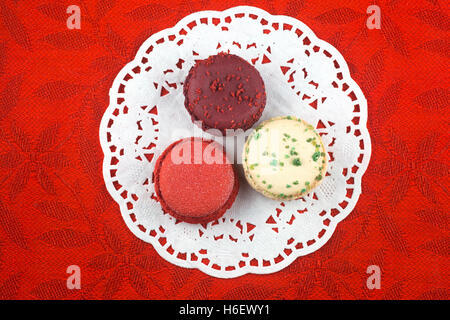 Christmas macarons, vanilla basil, frosted cranberry and mulled wine flavors on red tablecloth Stock Photo