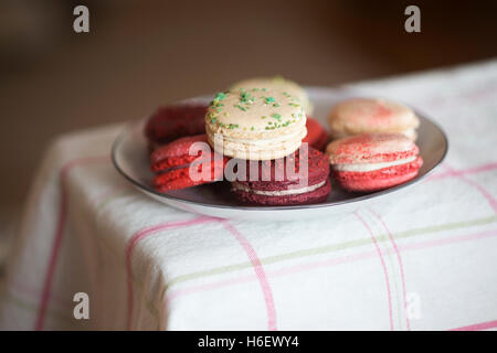 Christmas macarons - vanilla basil, frosted cranberry, mulled wine and candycane flavours on checked tablecloth Stock Photo