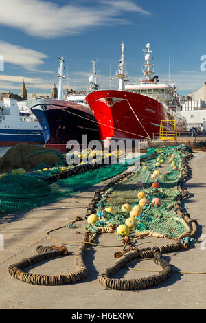 Moored trawlers in harbour with fishing nets boats docked on quayside [PT] Stock Photo