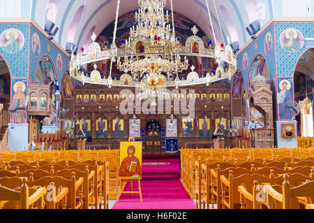 St Varvara Cathedral interior with colorfull paintings on the walls, wooden iconostasis and large golden chandelier, Paralimni Stock Photo