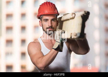 Smiling Carpenter Carrying A Large Wood Plank On His Shoulder Stock Photo
