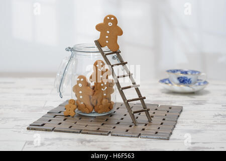 Gingerbread man at the top of a ladder about to jump into cookie jar Stock Photo