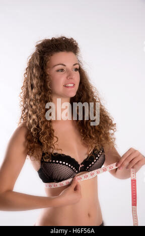 Teenage girl holding a tape measure under her bra to check her size in inches Stock Photo