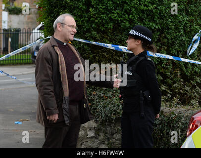 A police officer talks to a member of the public at the scene in Byron Avenue in Campsall, South Yorkshire, where the body believed to be that of a 13-year-old boy has been found following a fire in a shed. Stock Photo