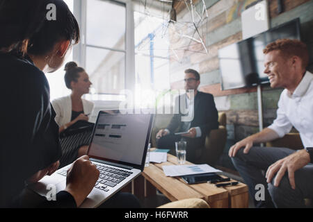 Businesswoman working on laptop while sitting in meeting with colleague. Business people in meeting room. Stock Photo