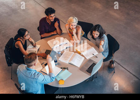 Group of young people studying together. Young students in cooperation with their academic assignment. Stock Photo
