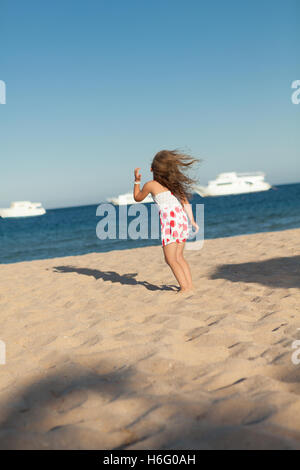 pretty little young girl searching in yellow sea sand Stock Photo