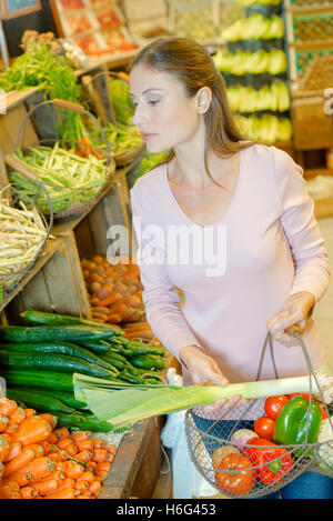 Lady shopping, holding wire basket of vegetables Stock Photo