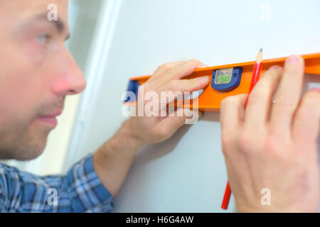 Using a spirit level to check a wall is straight Stock Photo