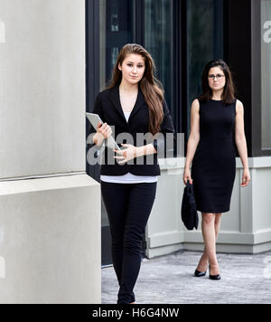 Two young women exiting office building Stock Photo