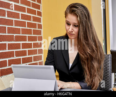 Young Woman typing on a laptop sitting outdoors Stock Photo
