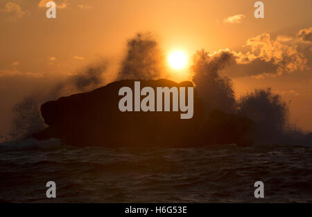 Dawn waves break over a large rock in Old Town Bay, St Mary's. Isles of Scilly Stock Photo