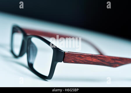 closeup of a pair of plastic and wooden rimmed eyeglasses on a white surface Stock Photo