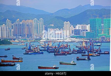 Cargo ships in the bay of Hong Kong await loading and unloading of cargo from their hulls. Stock Photo