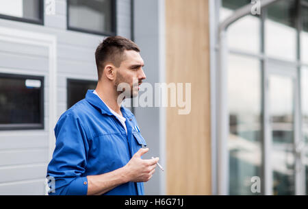 auto mechanic smoking cigarette at car workshop Stock Photo