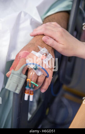 Close-up of Hand of a nurse as she comforts a patients hand with drips and plasters Stock Photo